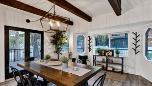A dining area with a wooden table, chairs, and a hanging light fixture. - Balboa at Big Bear #404 (Big Bear Lake)