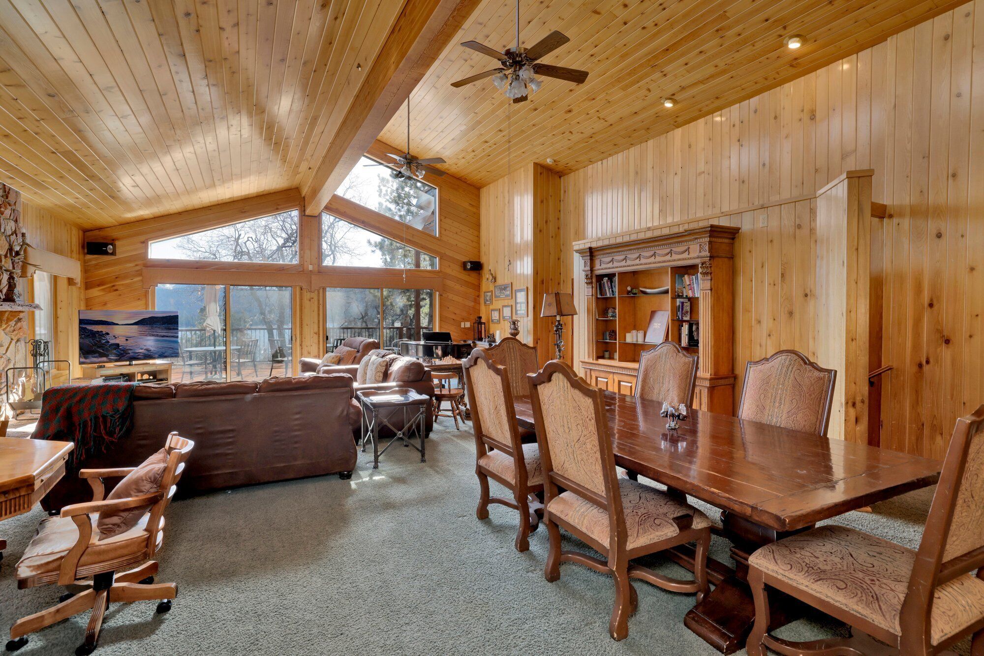 A spacious room with a large wooden dining table, multiple chairs, a sofa, and a television.