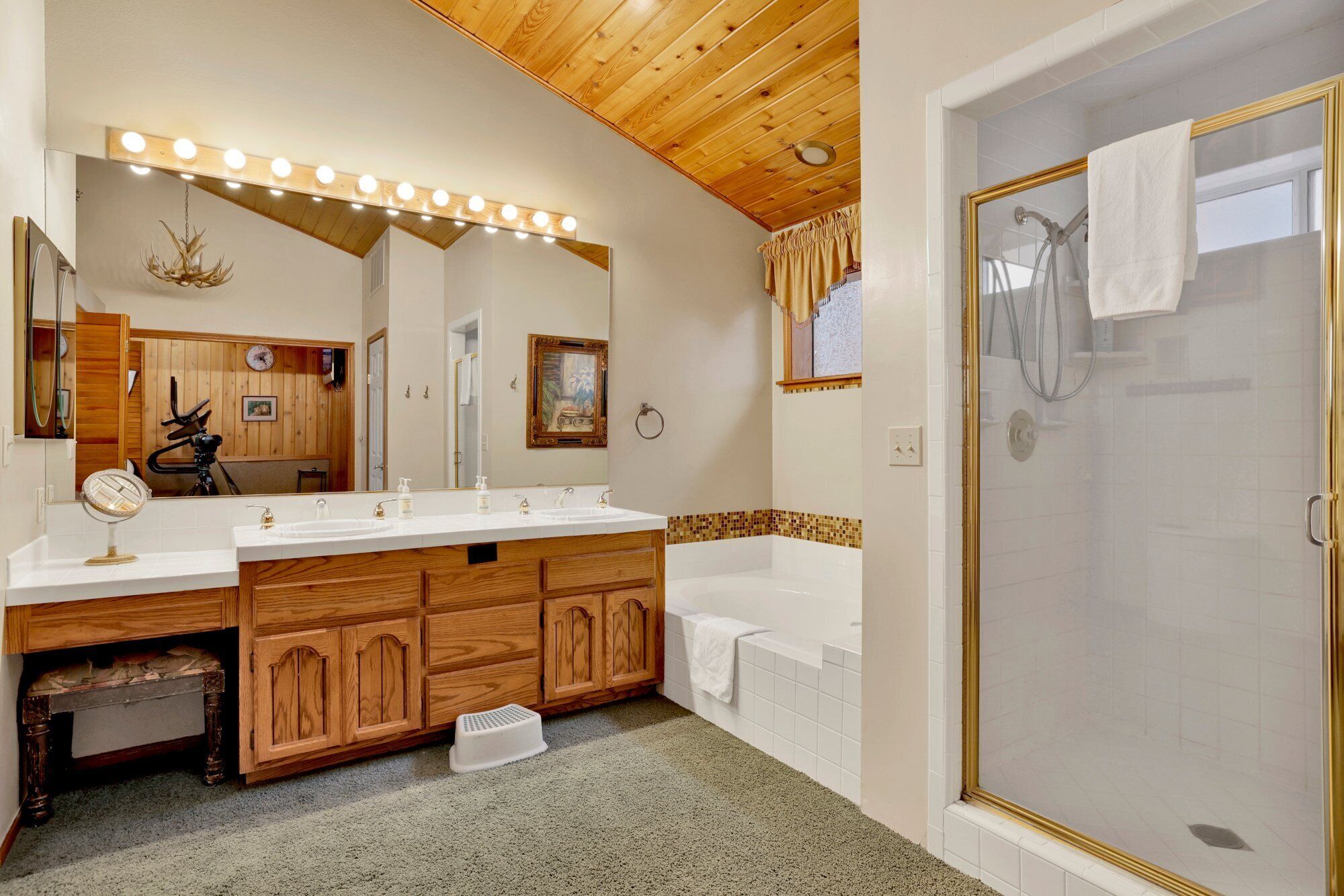 A bathroom with a double vanity, a large mirror, and a walk-in shower.