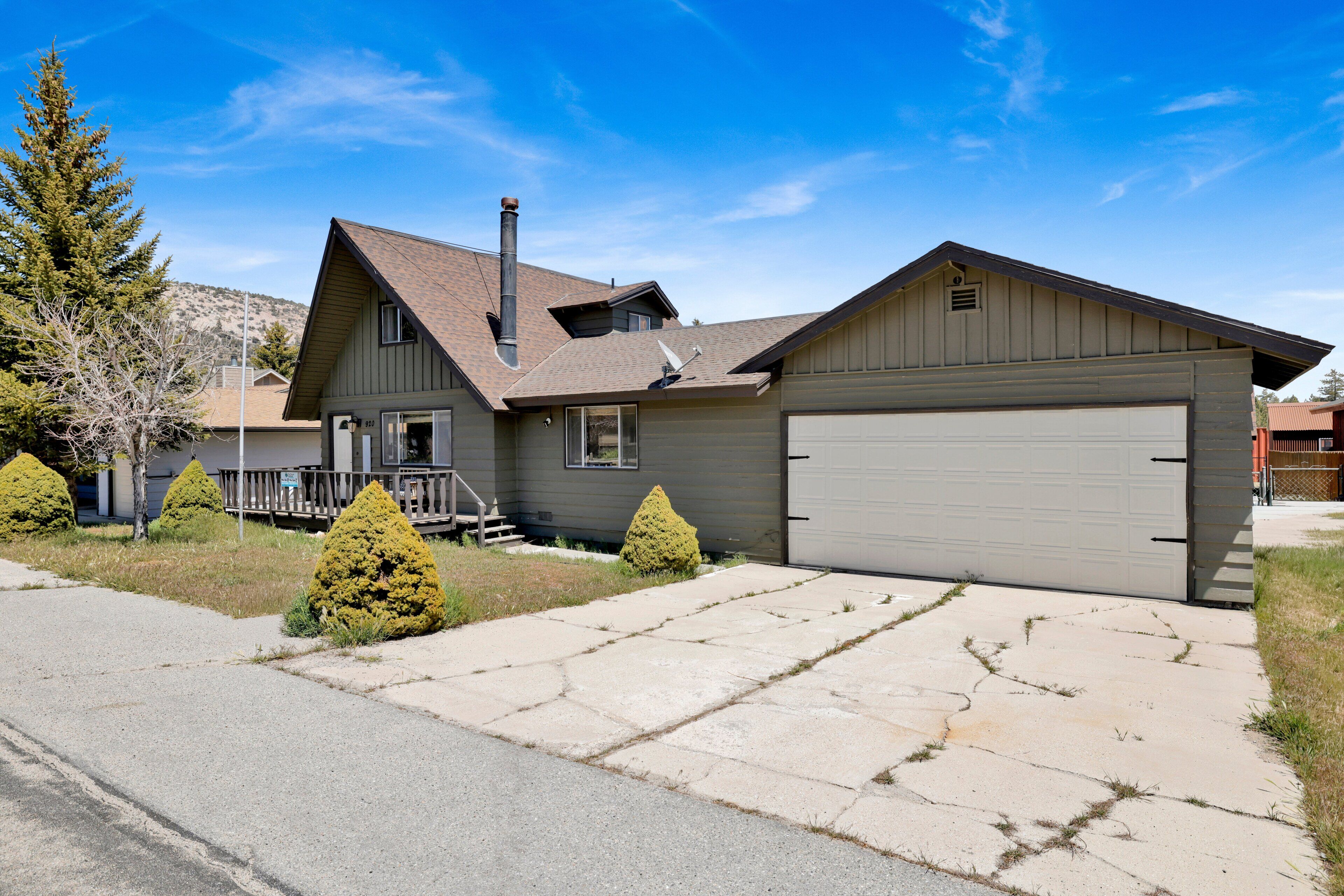 A residential house with a garage, a chimney, and a driveway with a sidewalk.