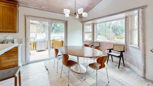 A spacious dining area with a wooden table and chairs, large windows, and a view of the outdoors. - Big Bear White Skies #674 (Big Bear Lake)