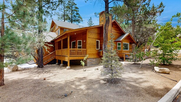 A wooden cabin with a porch, surrounded by pine trees. - Big Bear White Skies #674 (Big Bear Lake)