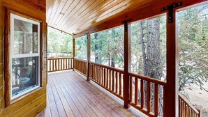 A wooden deck with a railing, large windows, and a view of trees. - Big Bear White Skies #674 (Big Bear Lake)