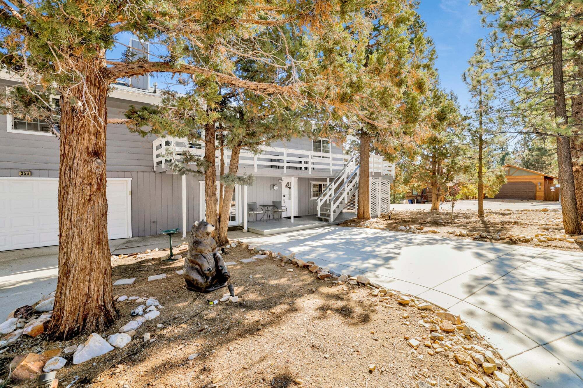 A residential property with a garage, a covered outdoor seating area, and a staircase leading to a second floor.