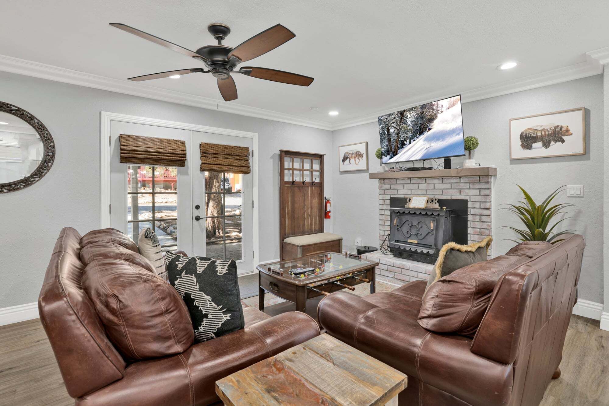 A living room with leather sofas, a fireplace, a television, and a ceiling fan.