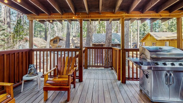 A covered deck with wooden railings, a grill, and seating. - Bristlecone Cottage #321 (Big Bear Lake)