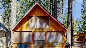 A wooden cabin with a number '42732' on the front, a bench outside, and a sign with a phone number. - Bristlecone Cottage #321 (Big Bear Lake)