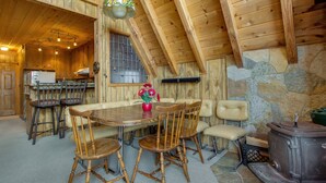A wooden interior with a dining table, chairs, a stove, and a kitchen area. - Castle Rock Cabin #2 (Big Bear Lake)