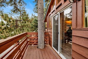 A wooden deck with a glass door leading to a room. - Castle Rock Cabin #178 (Big Bear Lake)