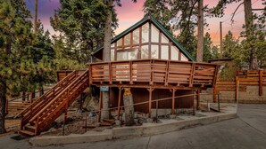 Une cabane en bois avec un étage supérieur en verre, entourée d’arbres.