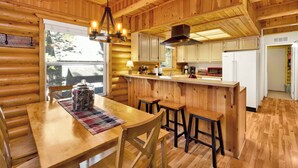 Ein Holzblockhaus-Interieur mit Essbereich, Küche und Bar.