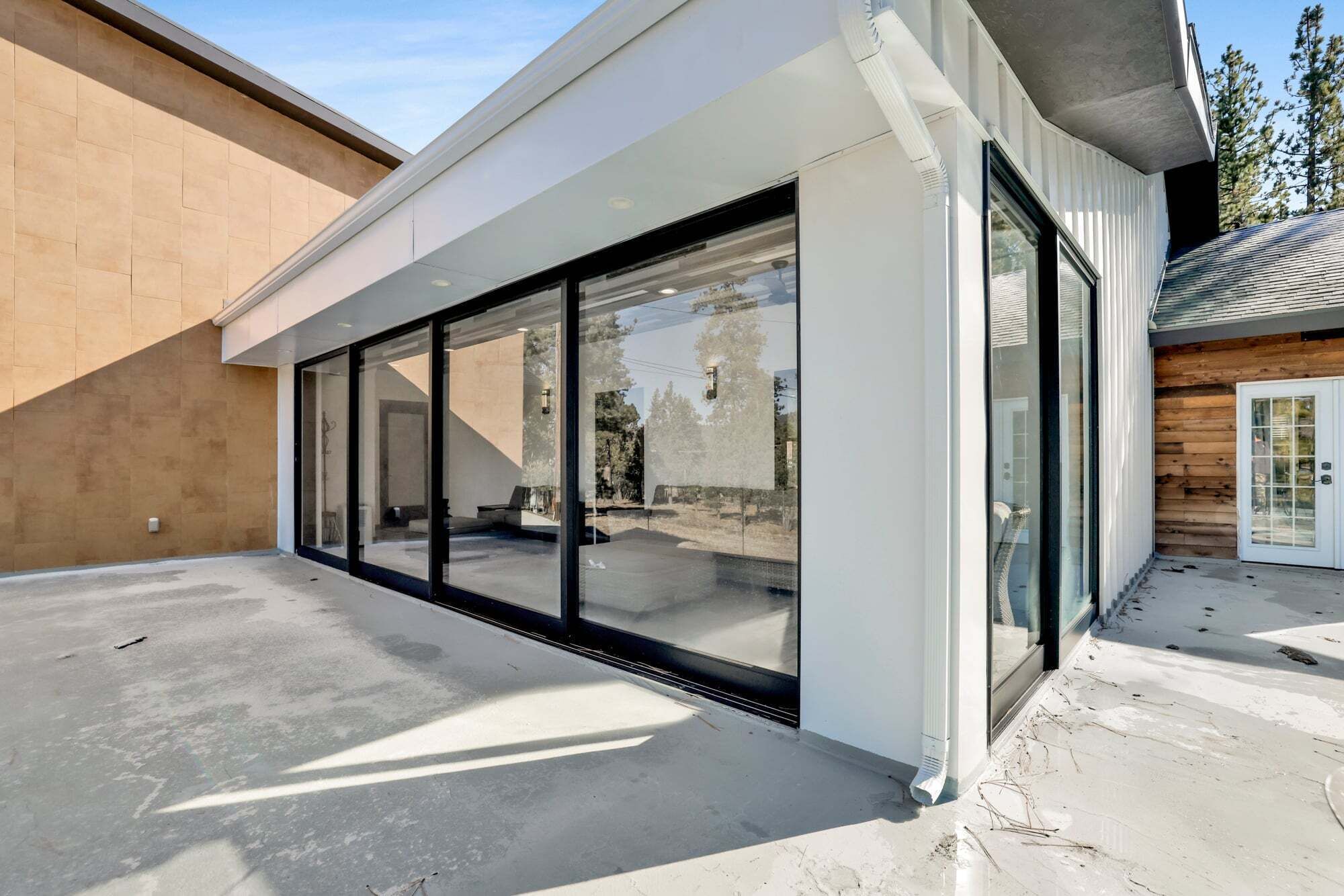 A modern building with large glass windows, a concrete floor, and a wooden exterior wall.