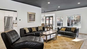 A modern living room with leather sofas, a coffee table, and a dining area with a table and chairs. - Hillside Hideaway #603 (Big Bear Lake)