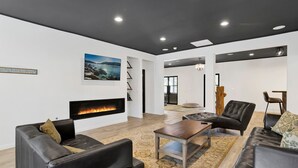 A modern living room with a fireplace, leather sofas, a coffee table, and a large window. - Hillside Hideaway #603 (Big Bear Lake)