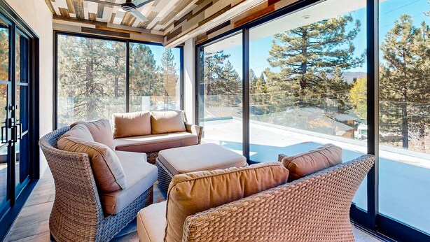 A modern interior with wicker furniture, large windows, and a ceiling fan. - Hillside Hideaway #603 (Big Bear Lake)
