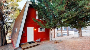 En rød hytte med skråtag, en hoveddør og en lille veranda.