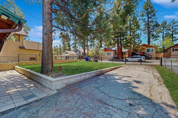 A residential area with houses, a paved driveway, and a grassy lawn.