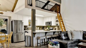 A spacious living area with a kitchen, a dining table, and a sofa. - Moose-in' Around (Big Bear Lake)