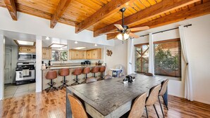 A spacious kitchen with wooden beams, a large dining table, and bar stools. - Mt Doble Dream Home #504 (Big Bear City)