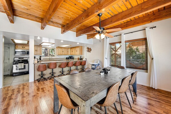 A spacious kitchen with wooden beams, a large dining table, and bar stools.