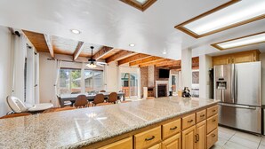 A modern kitchen with granite countertops, wooden cabinets, and a stainless steel refrigerator. - Mt Doble Dream Home #504 (Big Bear City)