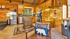 A cozy cabin-style kitchen with wooden cabinets, a refrigerator, stove, and a microwave. - Orchard Family Cabin #2560 (Big Bear Lake)