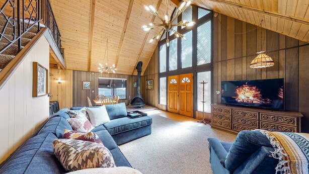 Een ruime woonkamer met een grote hoekbank, een open haard, een televisie en een trap naar een verdieping.
