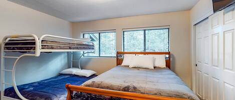 A bedroom with a bunk bed, a single bed, and a wardrobe.