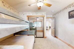 A room with bunk beds, a ceiling fan, and a door leading to another room. - Stony Creek Retreat #708 (Big Bear Lake)