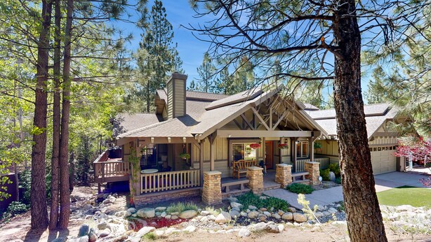 A cabin with a porch, stone foundation, and a stone pathway leading to the entrance.