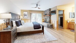 A bedroom with a bed, bedside table, lamp, and a fireplace.