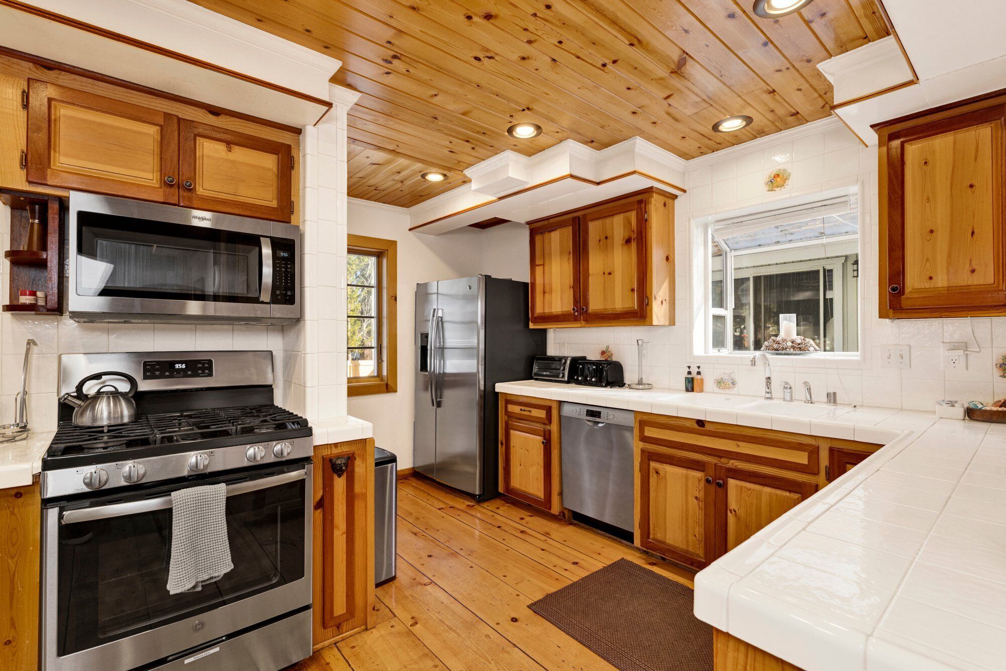 Une cuisine moderne avec des meubles en bois, des appareils électroménagers en acier inoxydable et une grande fenêtre.