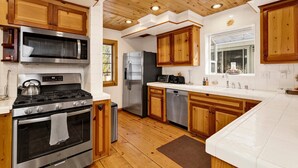 Une cuisine moderne avec des meubles en bois, des appareils électroménagers en acier inoxydable et une grande fenêtre.