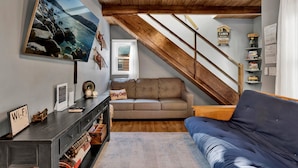 A cozy cabin interior with a wooden ceiling, a sofa, a blue couch, a wooden staircase, and a bookshelf. - The Summit at Sherwood #618 (Big Bear City)