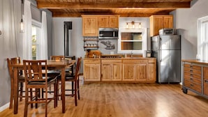 A kitchen with wooden cabinets, a stainless steel refrigerator, and a dining area with a table and chairs. - The Summit at Sherwood #618 (Big Bear City)