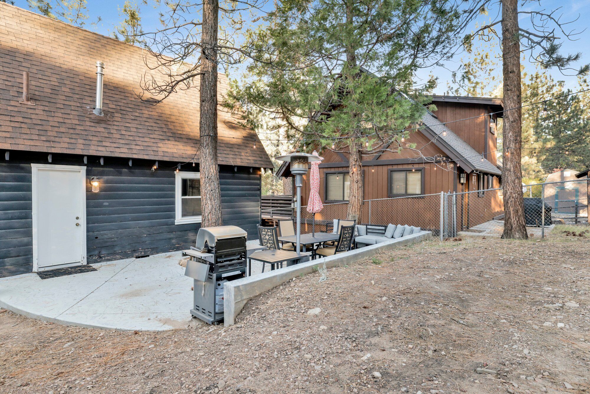 Una cabaña de madera con un patio amueblado y una parrilla.