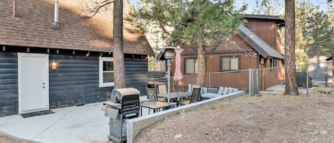 Una cabaña de madera con un patio amueblado y una parrilla.