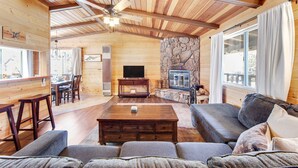 A wooden cabin interior with a stone fireplace, a television, and a dining area. - Vista Sugarloaf #329 (Sugarloaf)