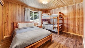 A wooden-paneled room with bunk beds, a window with curtains, and a bedside table. - Vista Sugarloaf #329 (Sugarloaf)