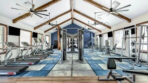 A gym with treadmills, weight machines, and ceiling fans.
