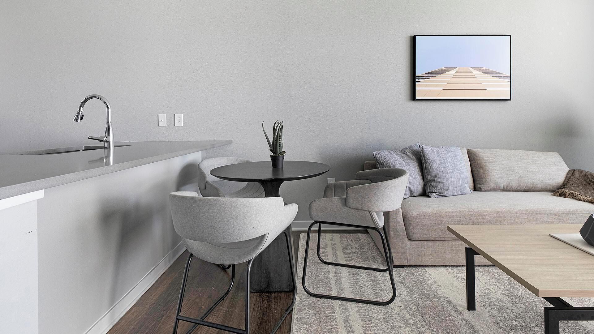 A modern kitchen with a built-in island, a round dining table, and a sofa with cushions.