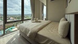 Habitación de hotel moderna con una cama grande, vistas a un parque acuático y un equipo de aire acondicionado en la pared.