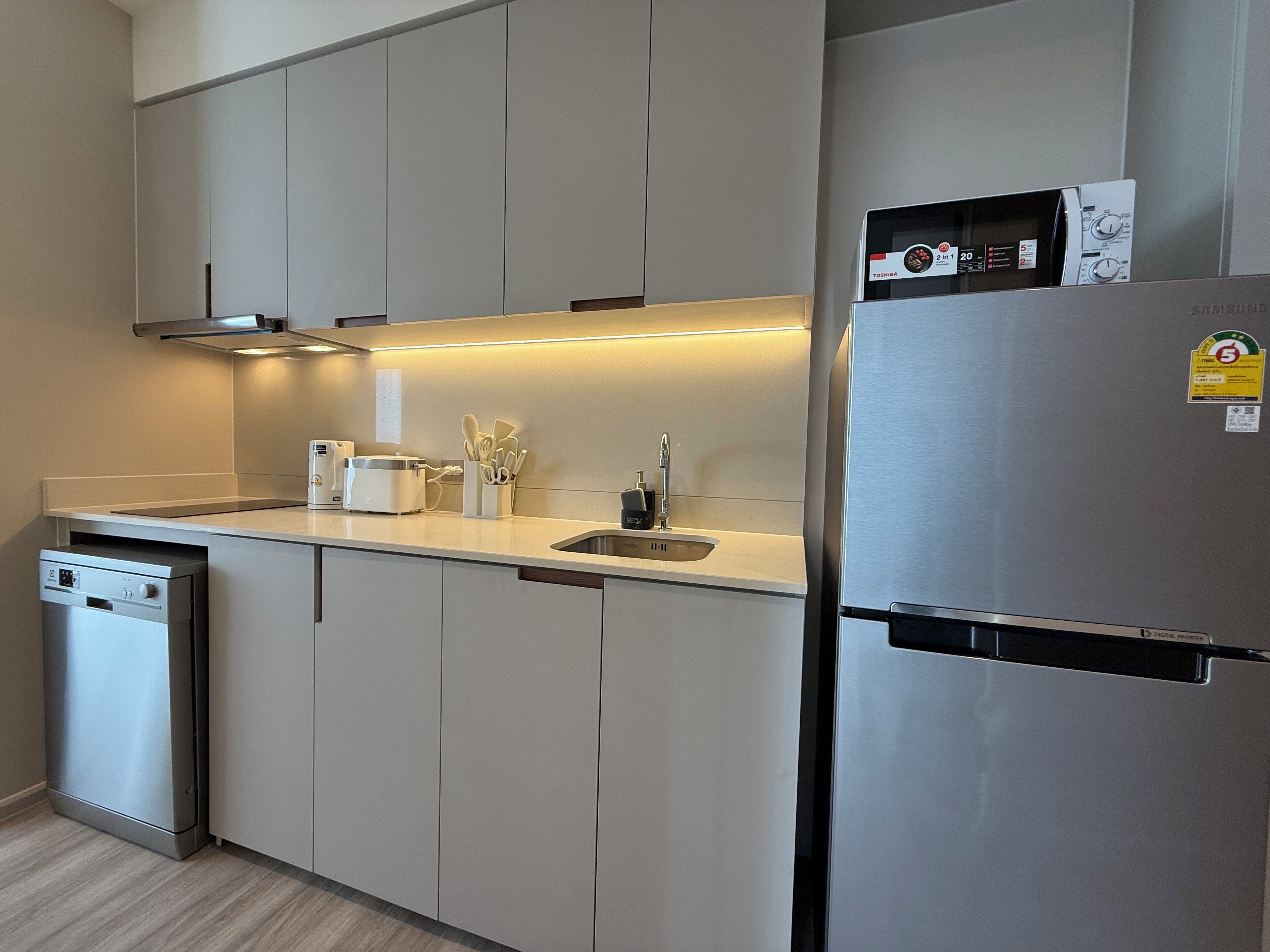 Una cocina moderna con electrodomésticos de acero inoxidable, lavavajillas y microondas.