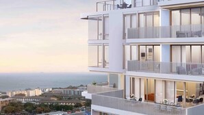 Un edificio moderno de varios pisos, con balcones, ventanas amplias y vista al mar.