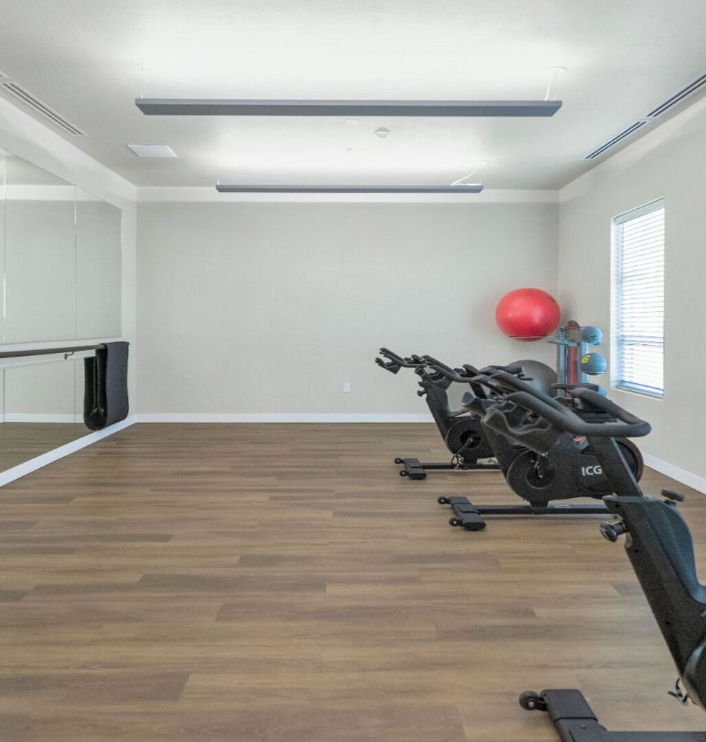 Ett gym med träningsutrustning, en röd träningsboll och ett fönster med persienner.