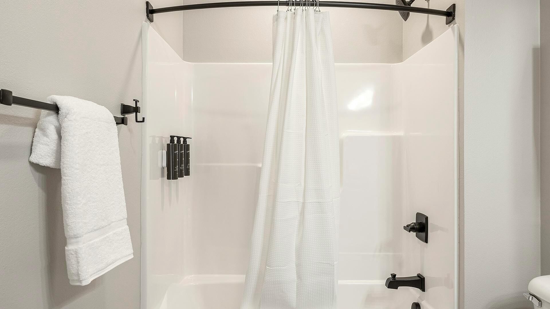 Un bany modern amb una cabina de dutxa de vidre, una barra de tovalloles i un dosificador de sabó.