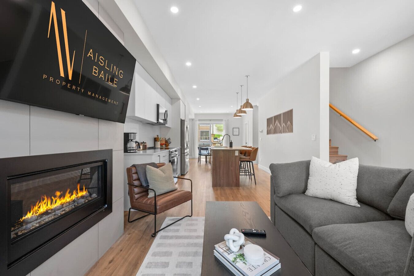 A modern living room with a fireplace, a sofa, a coffee table, and a kitchen in the background.