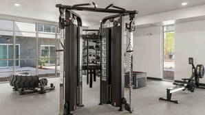 A gym with a squat rack, cable machine, and rowing machine. - Landing | Chic 1BD, Gym, Pool (Phoenix)