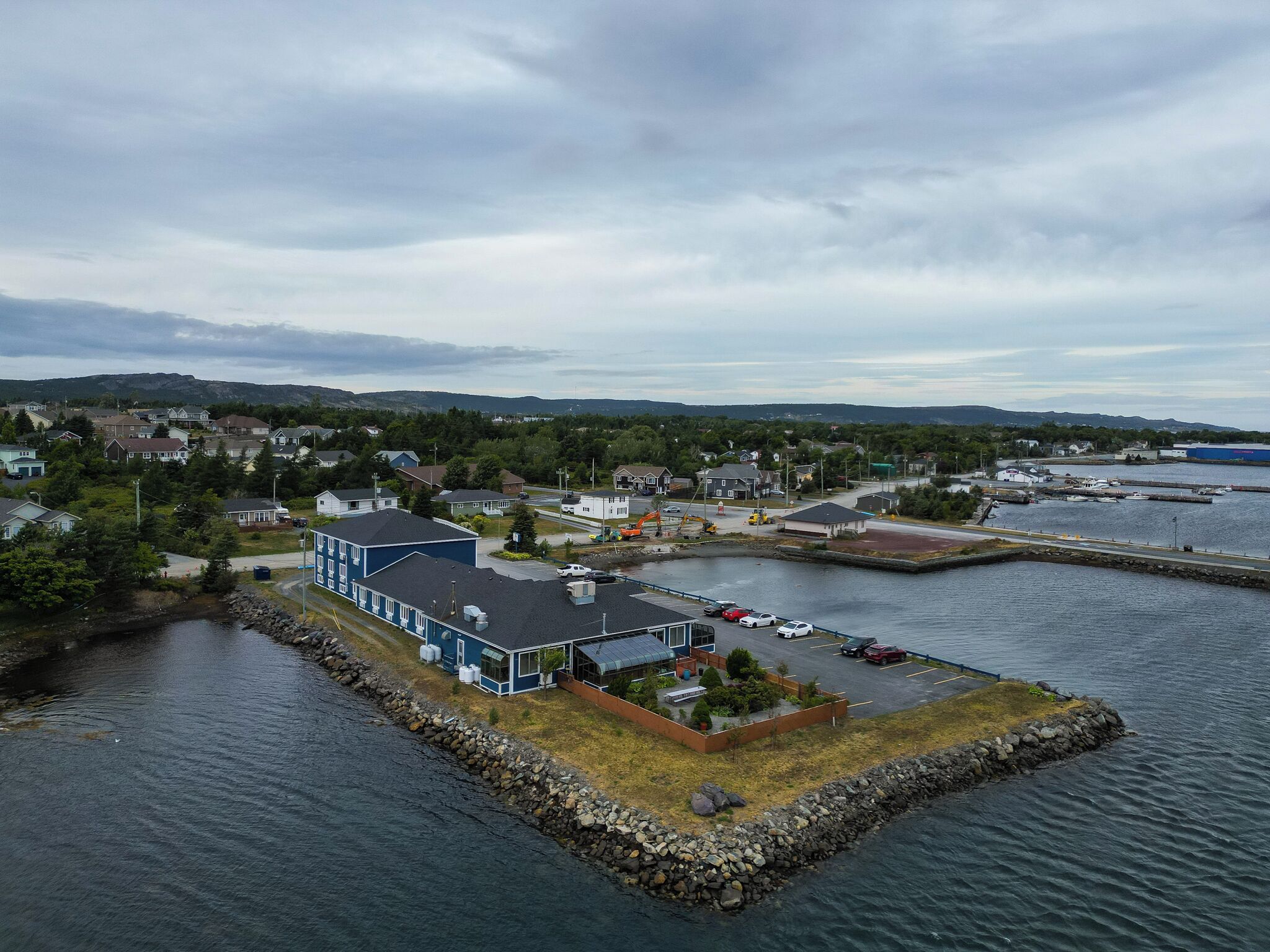 Une propriété située au bord de l’eau, dotée d’un quai, d’un espace de stationnement et d’un bâtiment à la façade bleue.