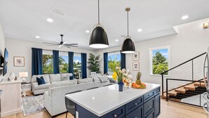 Una cocina moderna con una isla central, muebles oscuros y vistas al exterior.